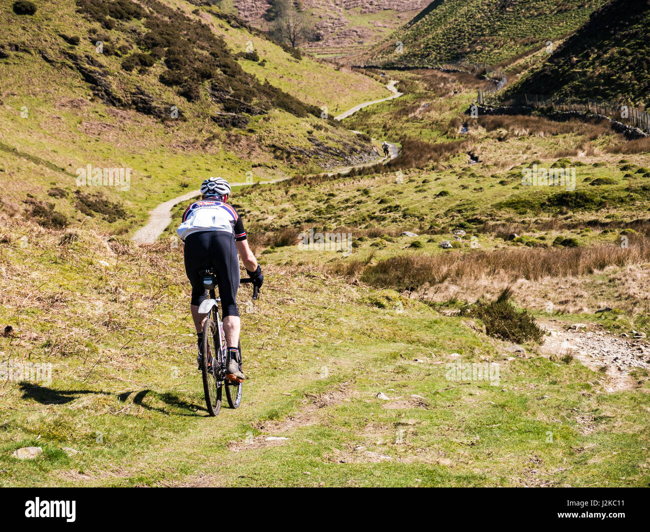 A Mountain biker follows the path of Nannycatch rd, in the Lake District, Cumbria, England Stock Photo