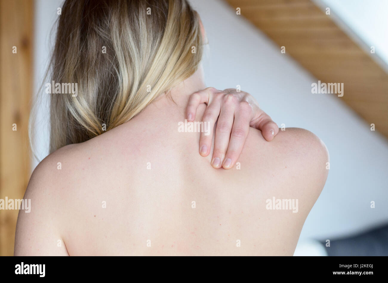 Rear upper body view of young woman rubbing painful shoulder with hand Stock Photo Alamy
