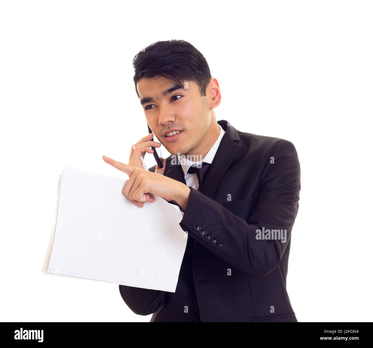 Arrogant young man with black hair in white shirt and black suit with tie  holding papers and talking on the phone on white background Stock Photo -  Alamy
