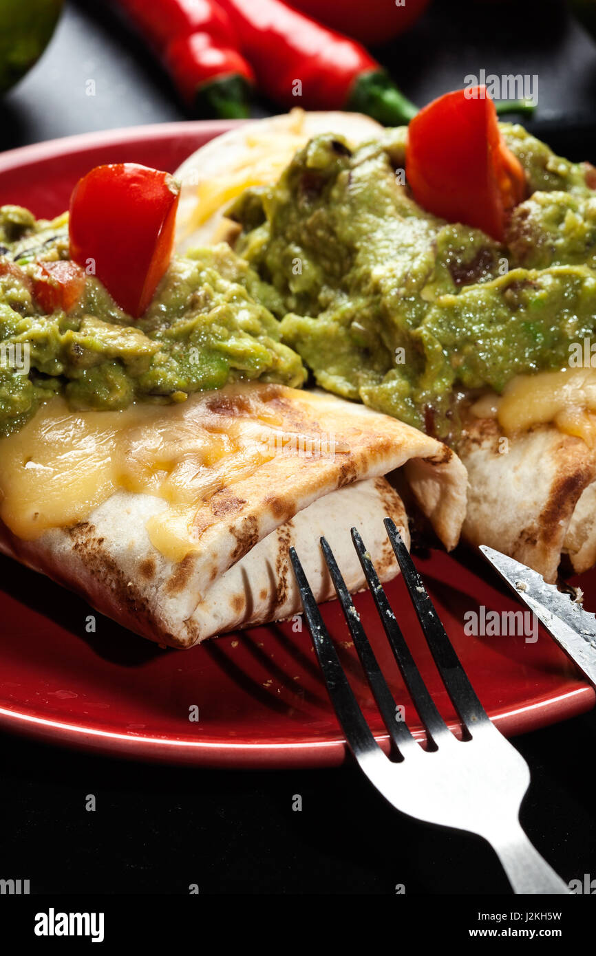 Mexican chimichanga with guacamole dip on a red plate Stock Photo