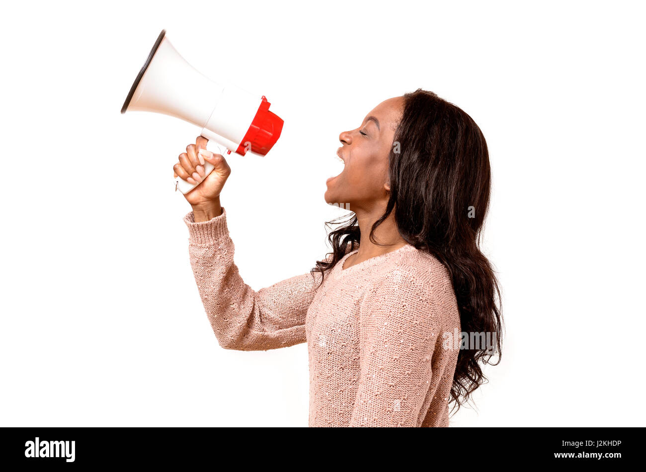 Angry young African woman yelling into a megaphone as she makes her grievances known at a demonstration or rally, side view on white Stock Photo