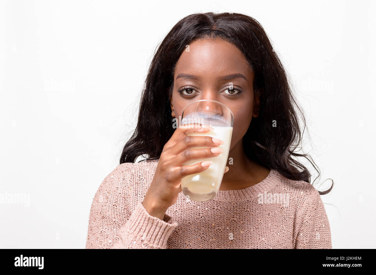 Young African woman drinking a glass of fresh milk in a healthy diet and  nutrition concept as she looks straight ahead at the camera, head and  shoulde Stock Photo - Alamy