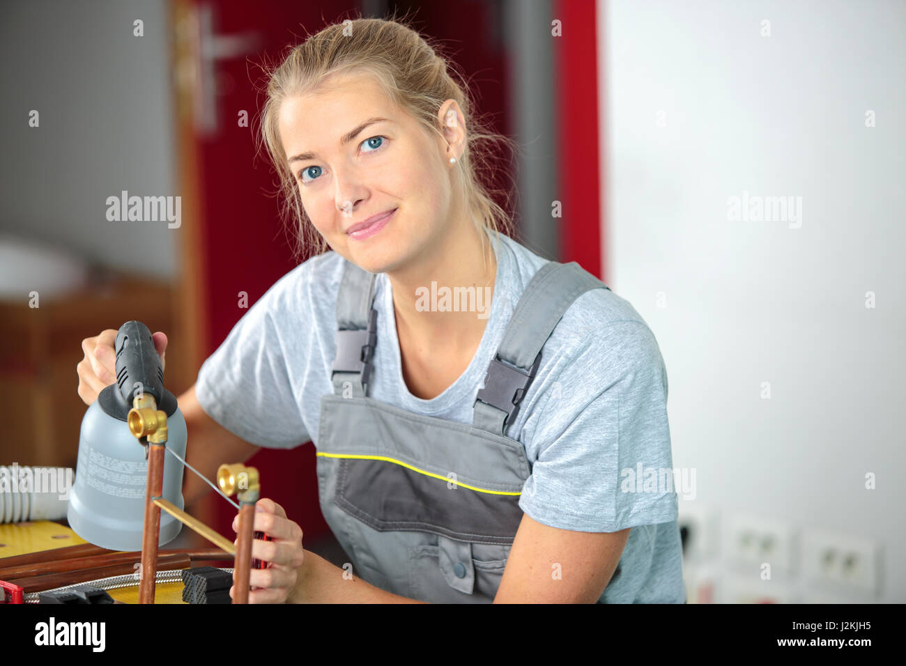 Female worker heating copper pipe Stock Photo