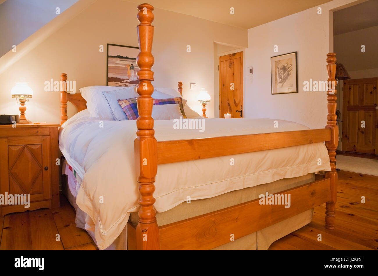 Queen size bed on wooden frame with tall bedposts in master bedroom on the  upstairs floor inside a Canadiana cottage style log home Stock Photo - Alamy