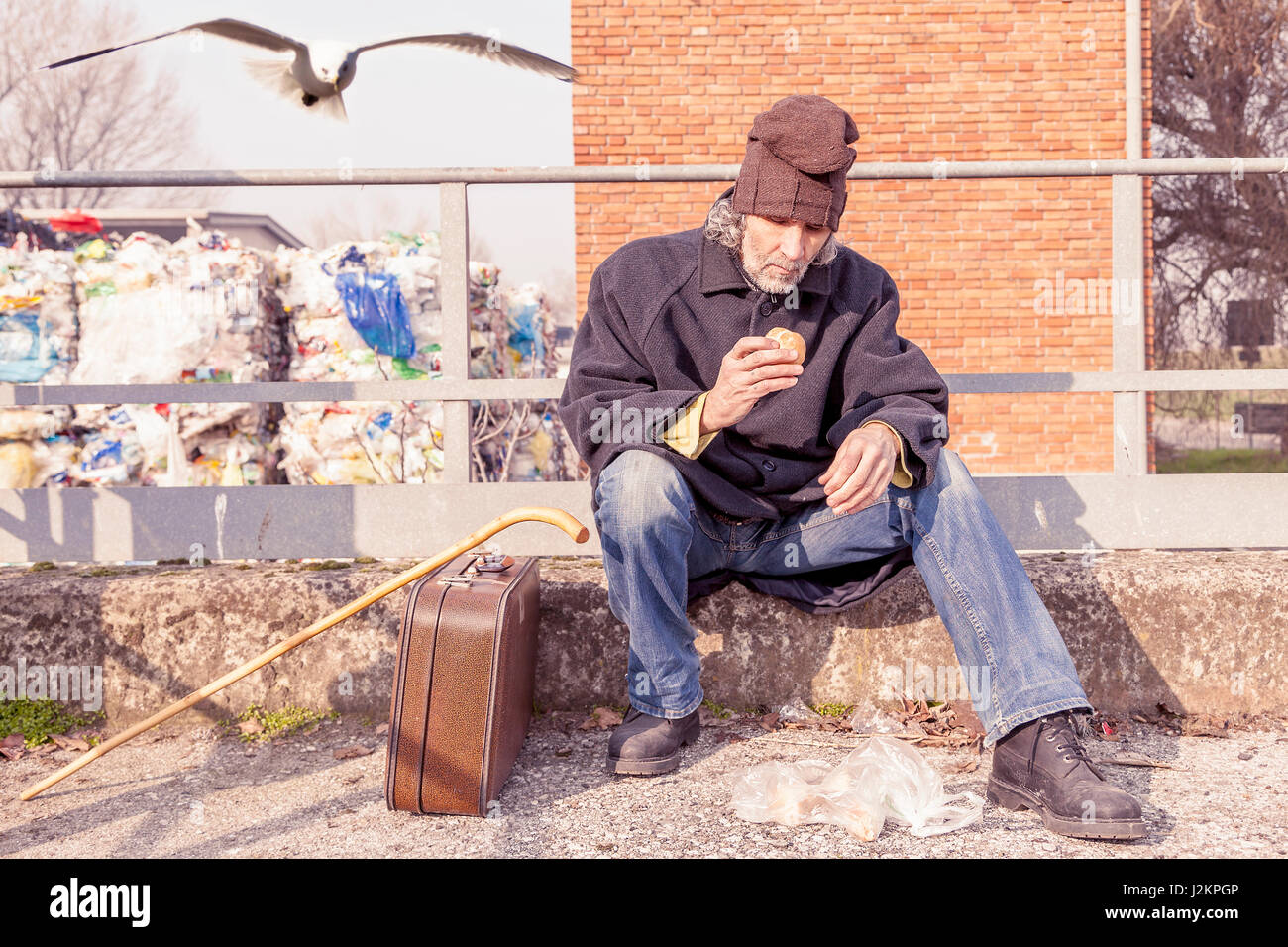 tramp eating bread sitting in landfills Stock Photo