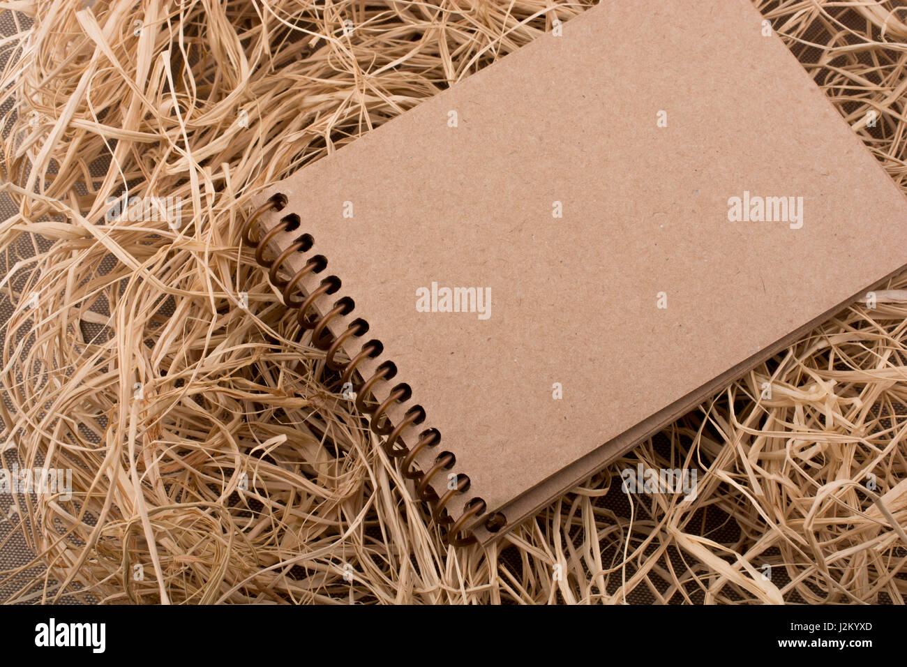 Spiral notebook placed on a straw background Stock Photo - Alamy