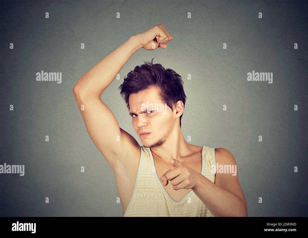 Closeup portrait of young man, smelling, sniffing his armpit, something stinks, bad, foul odor, pointing finger at camera isolated on gray background. Stock Photo