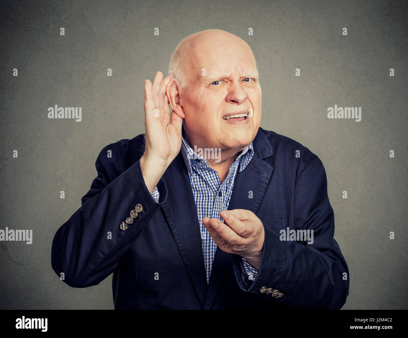 Senior man, hard of hearing, placing hand on ear asking someone to speak up Stock Photo