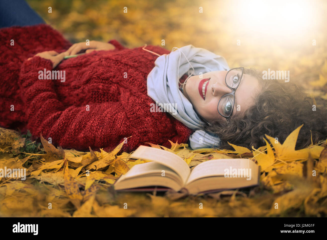 Woman with book laying on leaves Stock Photo