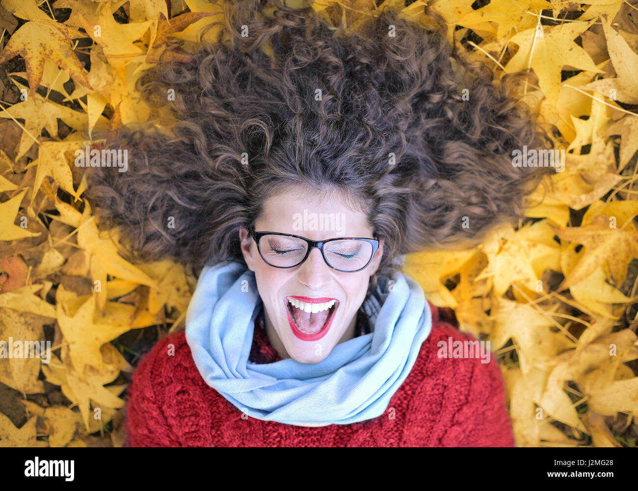 Smiling woman laying on leaves Stock Photo