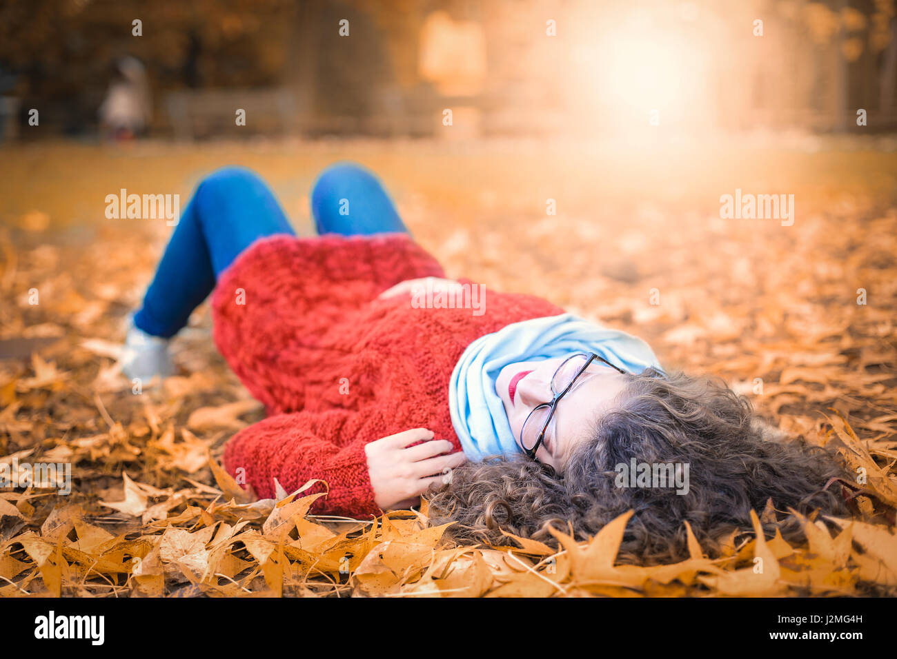 Woman with glasses laying in leaves Stock Photo