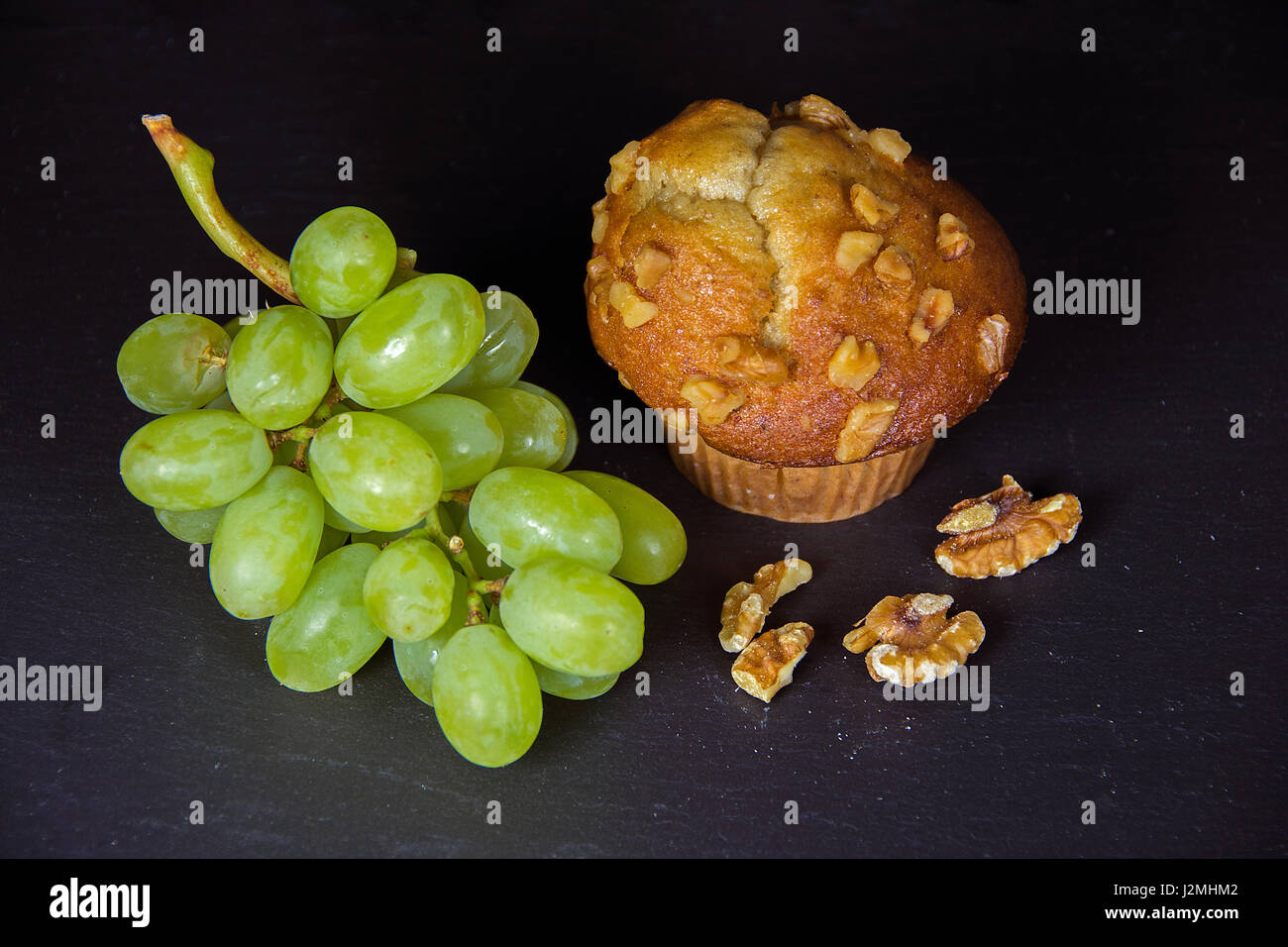 walnut muffin and green grape bunch on black slate Stock Photo Alamy