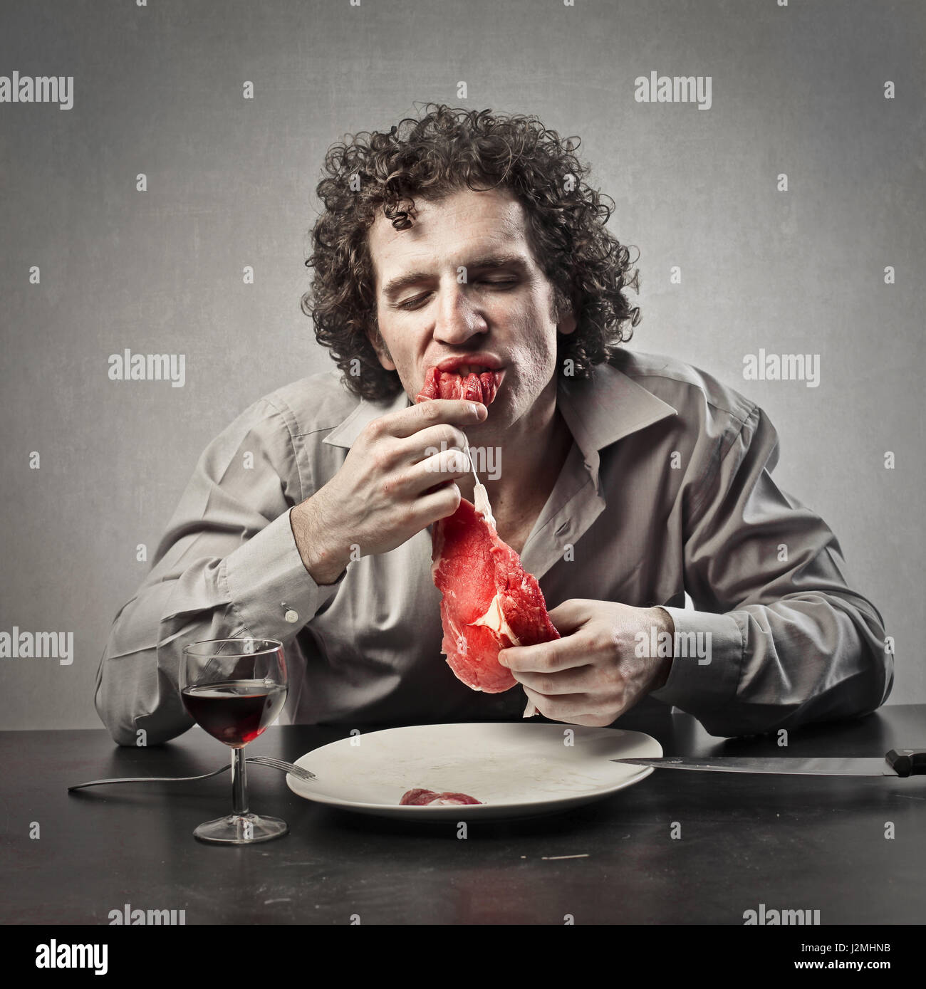 Man eating raw meat Stock Photo