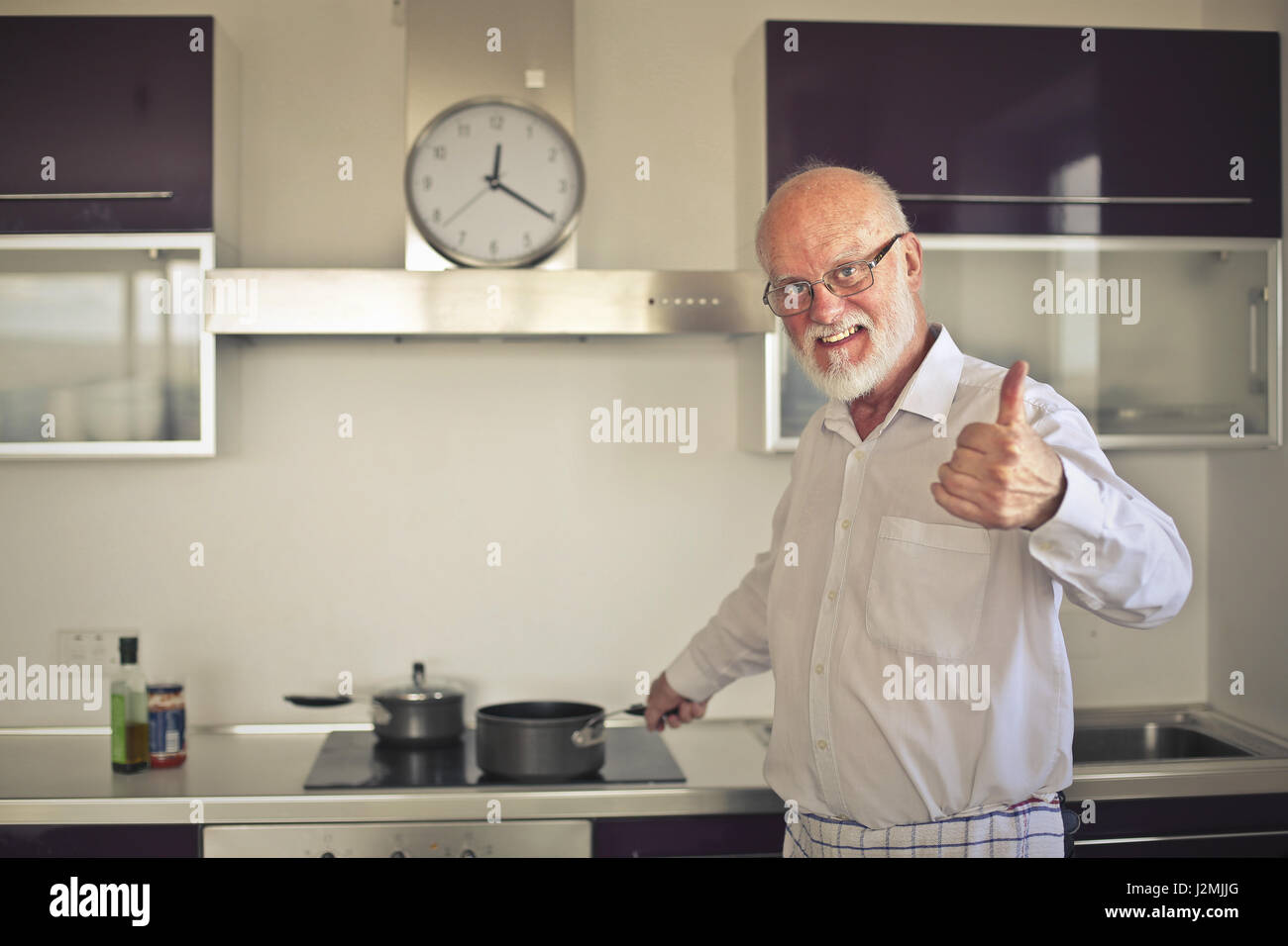 Old man cooking and showing like sign Stock Photo
