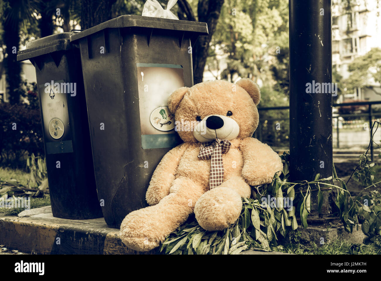 The teddy-bear was throw away sitting byside the garbage trash Stock Photo