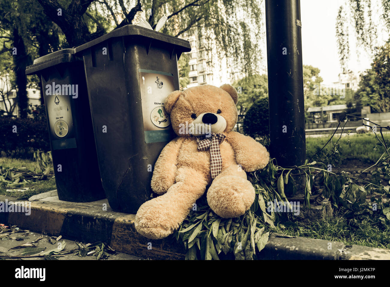 The teddy-bear was throw away sitting beside the garbage trash Stock Photo