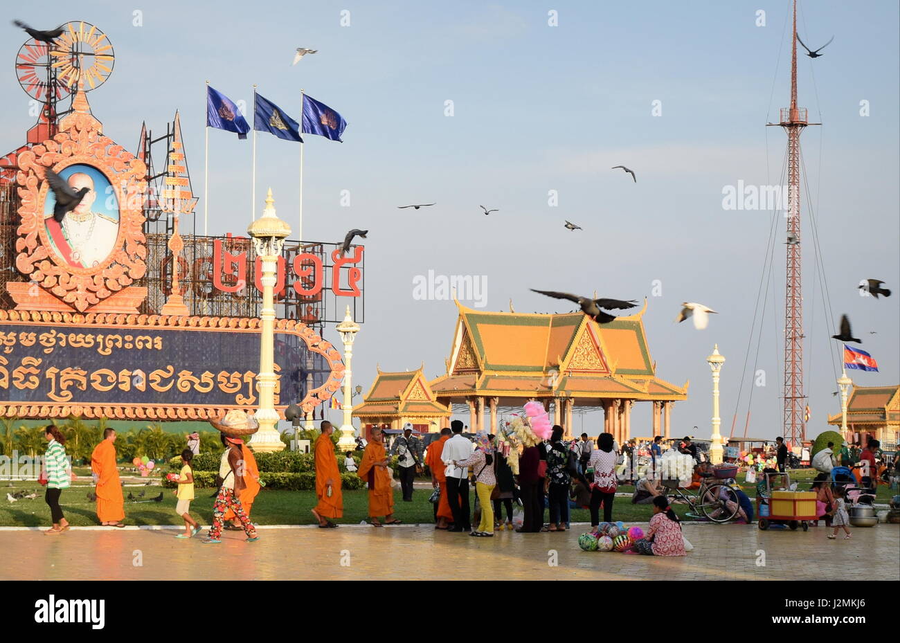 Phnom Penh Royal palace square real people and Buddhist monks, with Khmer calligraphy and monument for the king - Cambodia Stock Photo