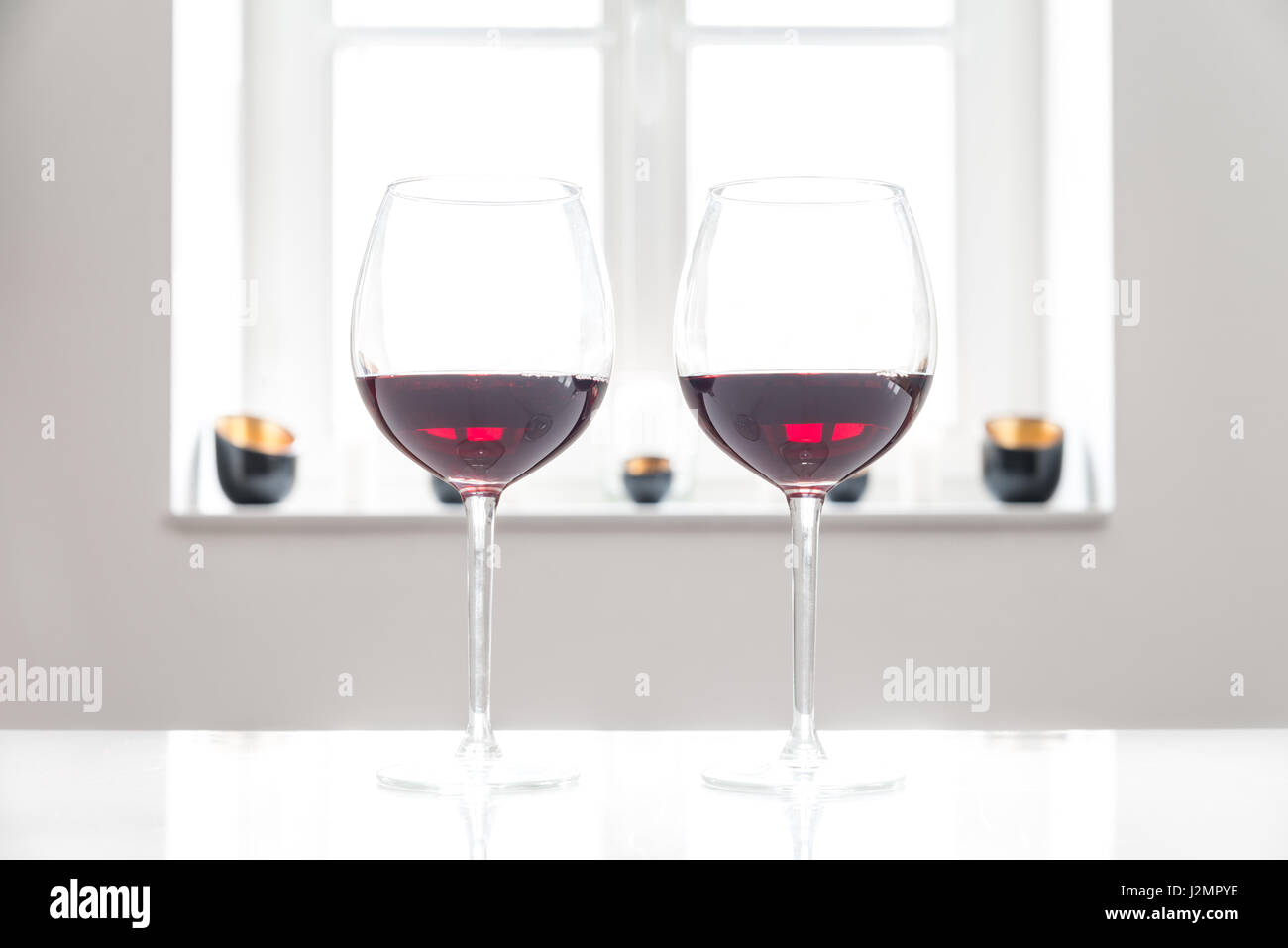 Two glasses with red wine on white table with white background and ...