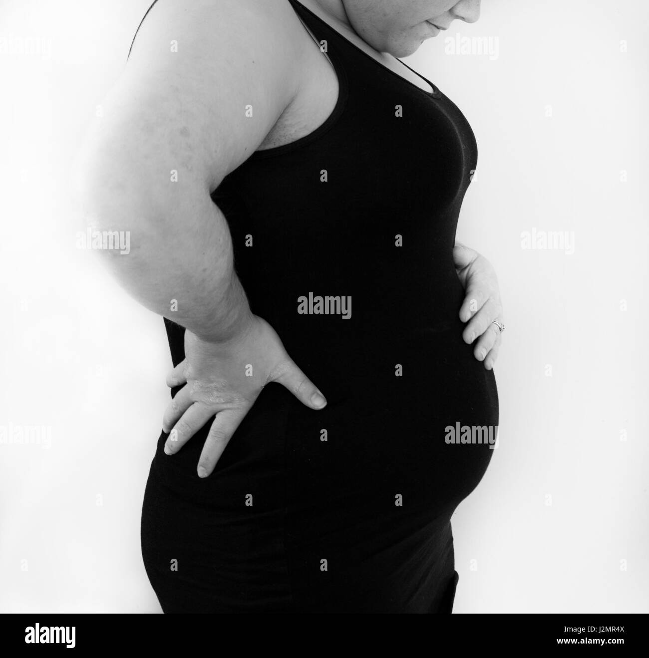 A newly pregnant woman looks down at her small bump Stock Photo