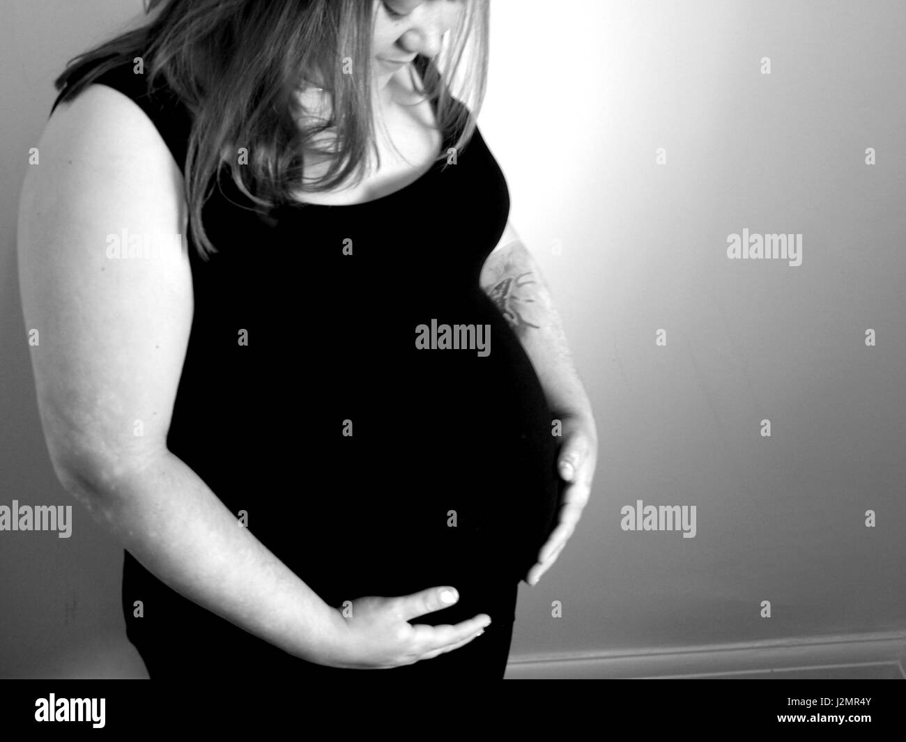 A heavily pregnant woman cradles her unborn child. Stock Photo