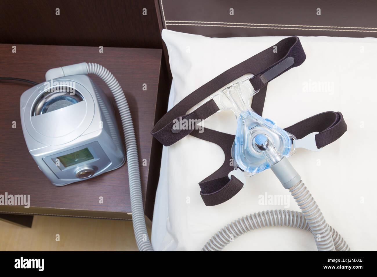 Sleep apnea CPAP headgear mask and hose on white pillow attaching to