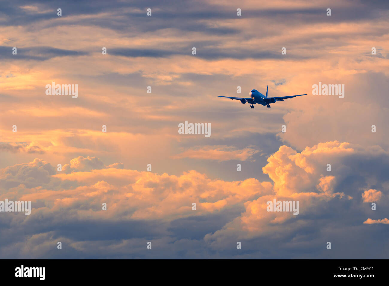 Commercial passenger airplane coming in for landing against beautiful colorful sunset, color and contrast enhanced Stock Photo