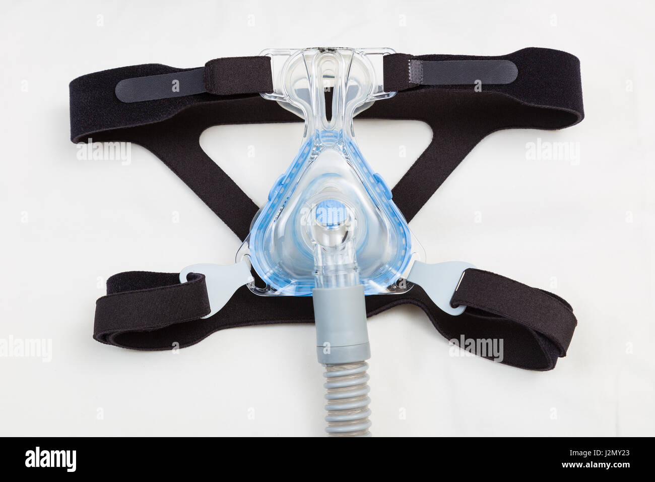Sleep apnea CPAP mask and hose on white pillow background, to use with