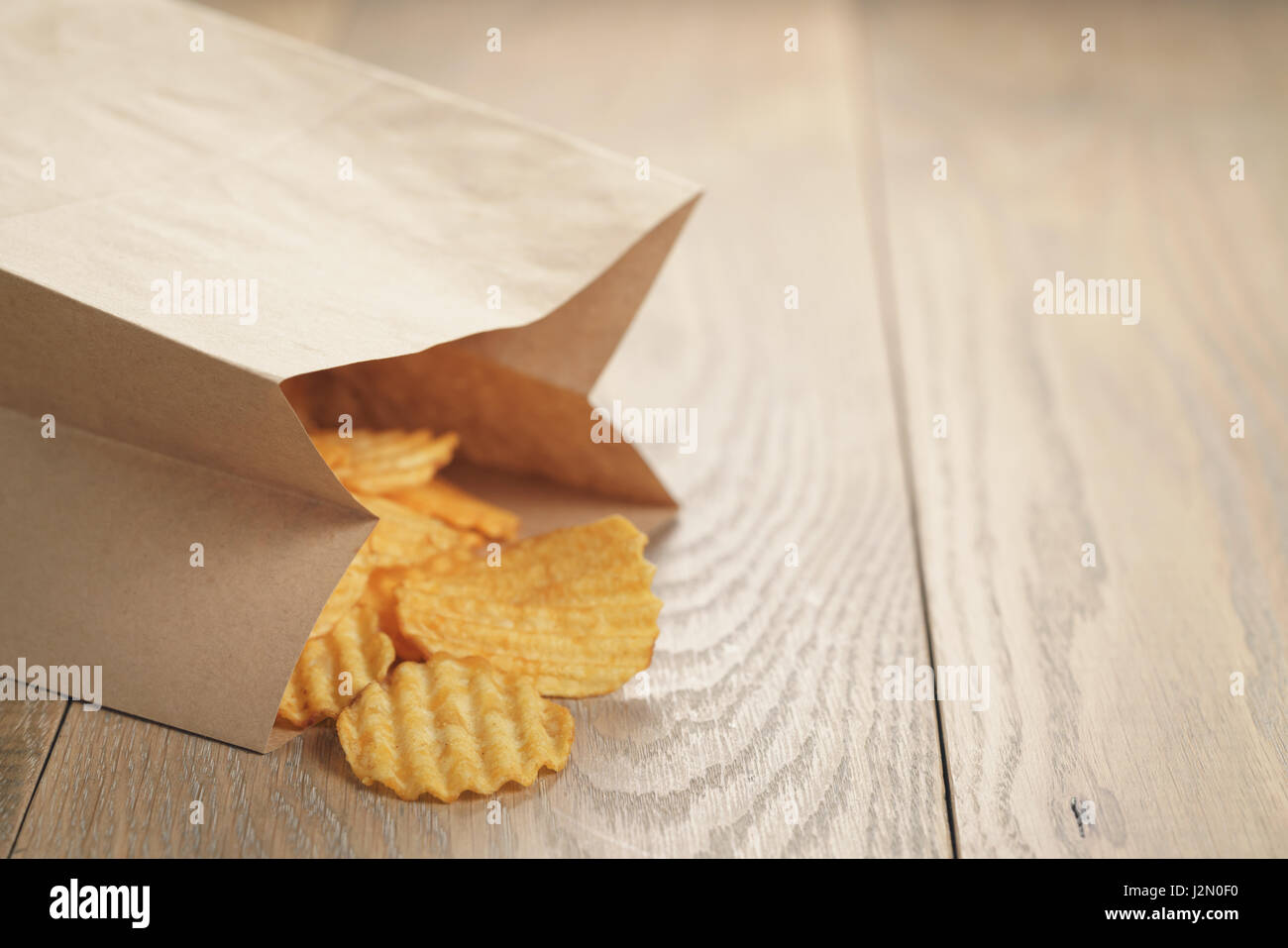 rippled potato chips with paprika in paper bag, shallow focus Stock