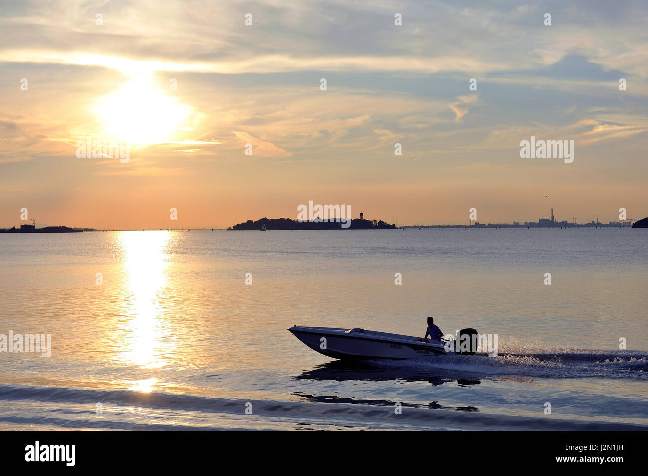romantic view of the lagoon of Venice seen from the shore, at sunset, with fishing boats, piers and moorings Stock Photo