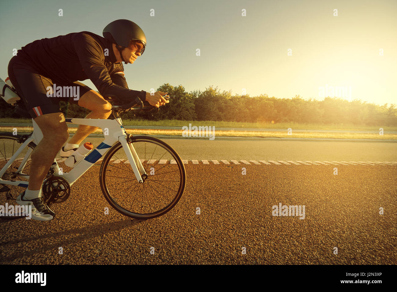 Side view of the racer riding a bicycle on the empty road in the ...