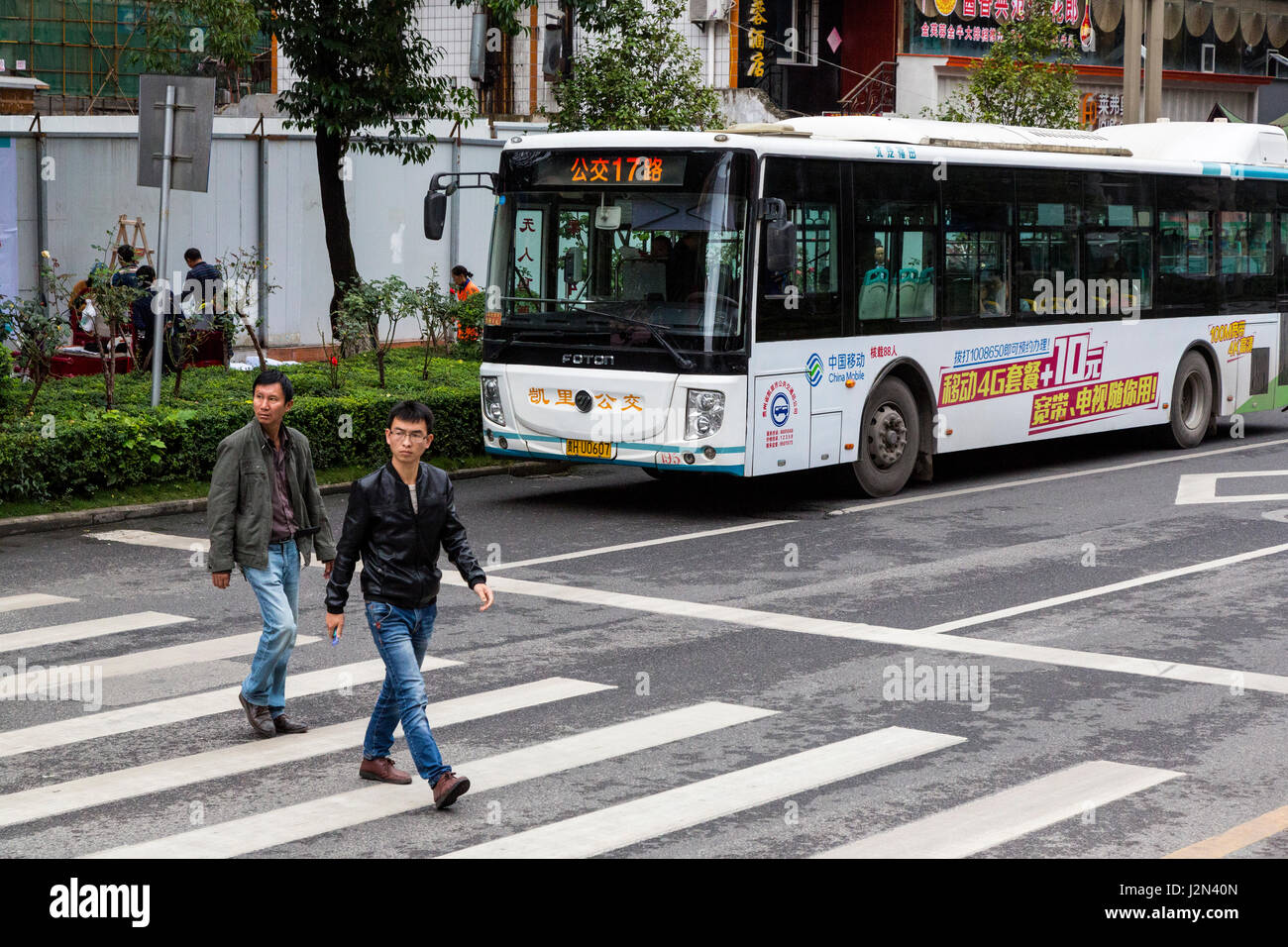 Kaili, Guizhou, China.  Municipal Bus, Men Crossing the Street. Stock Photo