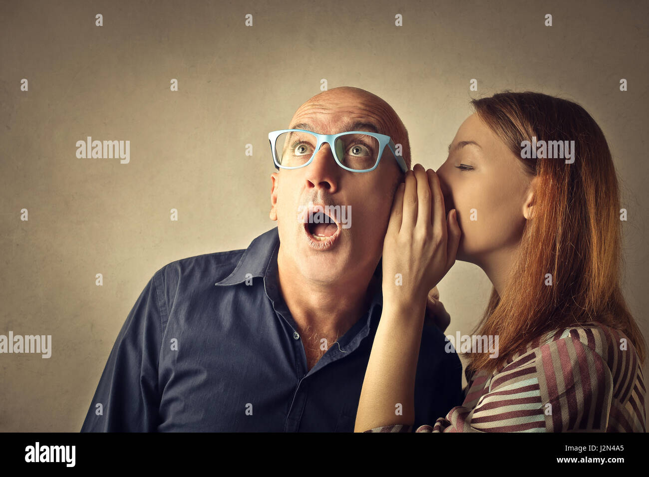 Woman whispering to bald man Stock Photo