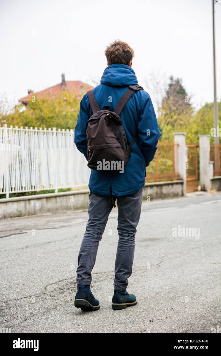 Teenage boy walking alone in street with backpack Stock Photo - Alamy