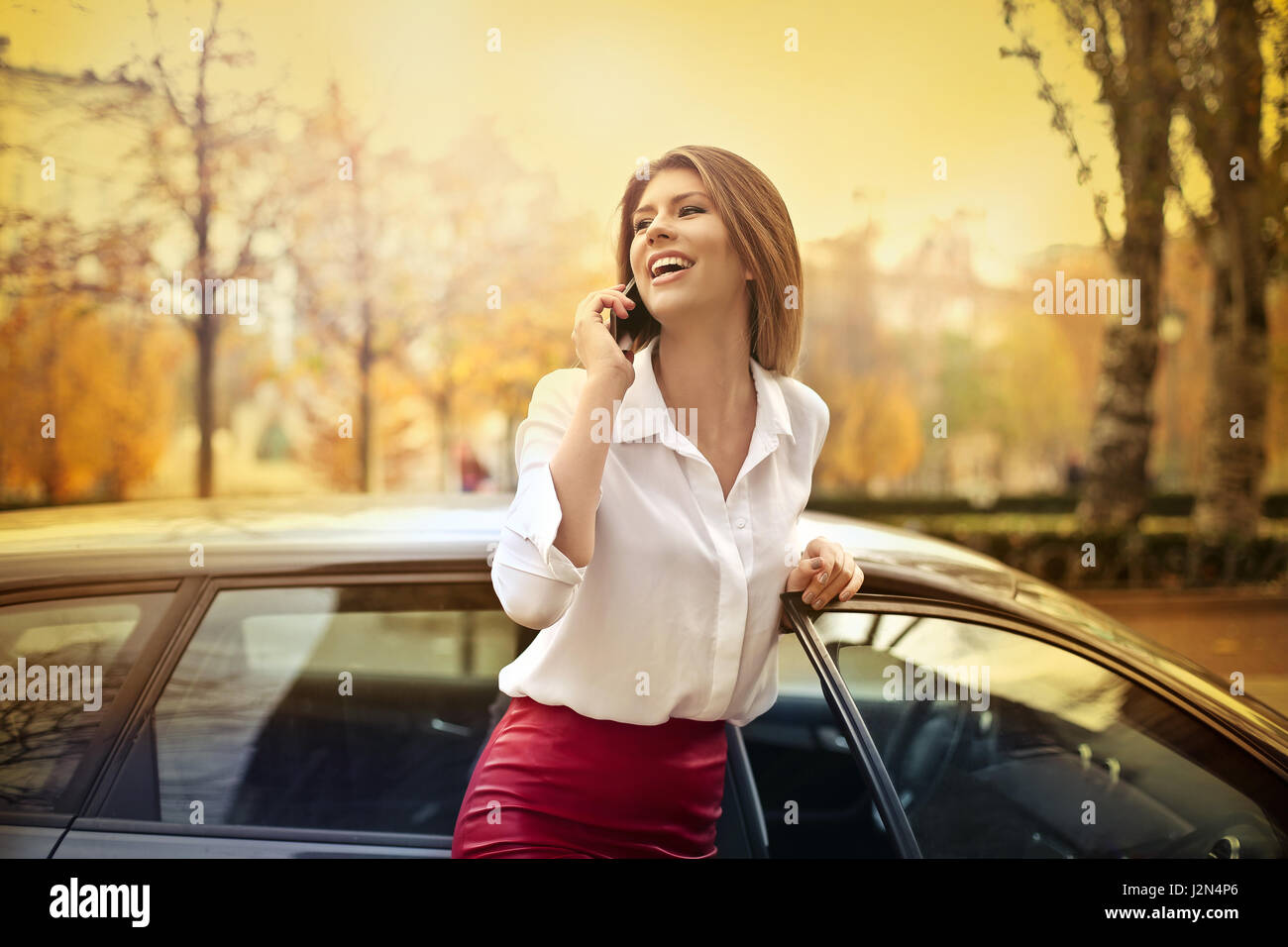 Happy woman telephoning next to car Stock Photo