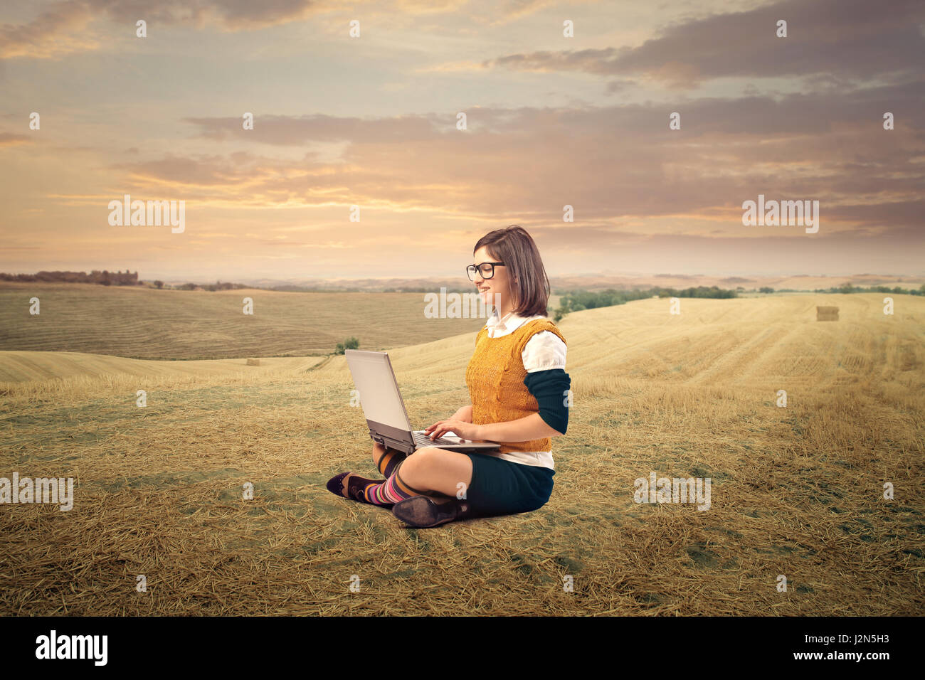 Woman with laptop on field Stock Photo