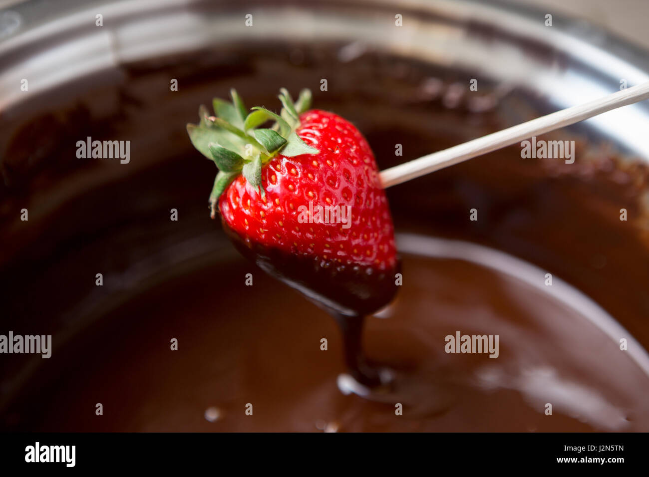 Dipping fresh strawberries in dark chocolate Stock Photo