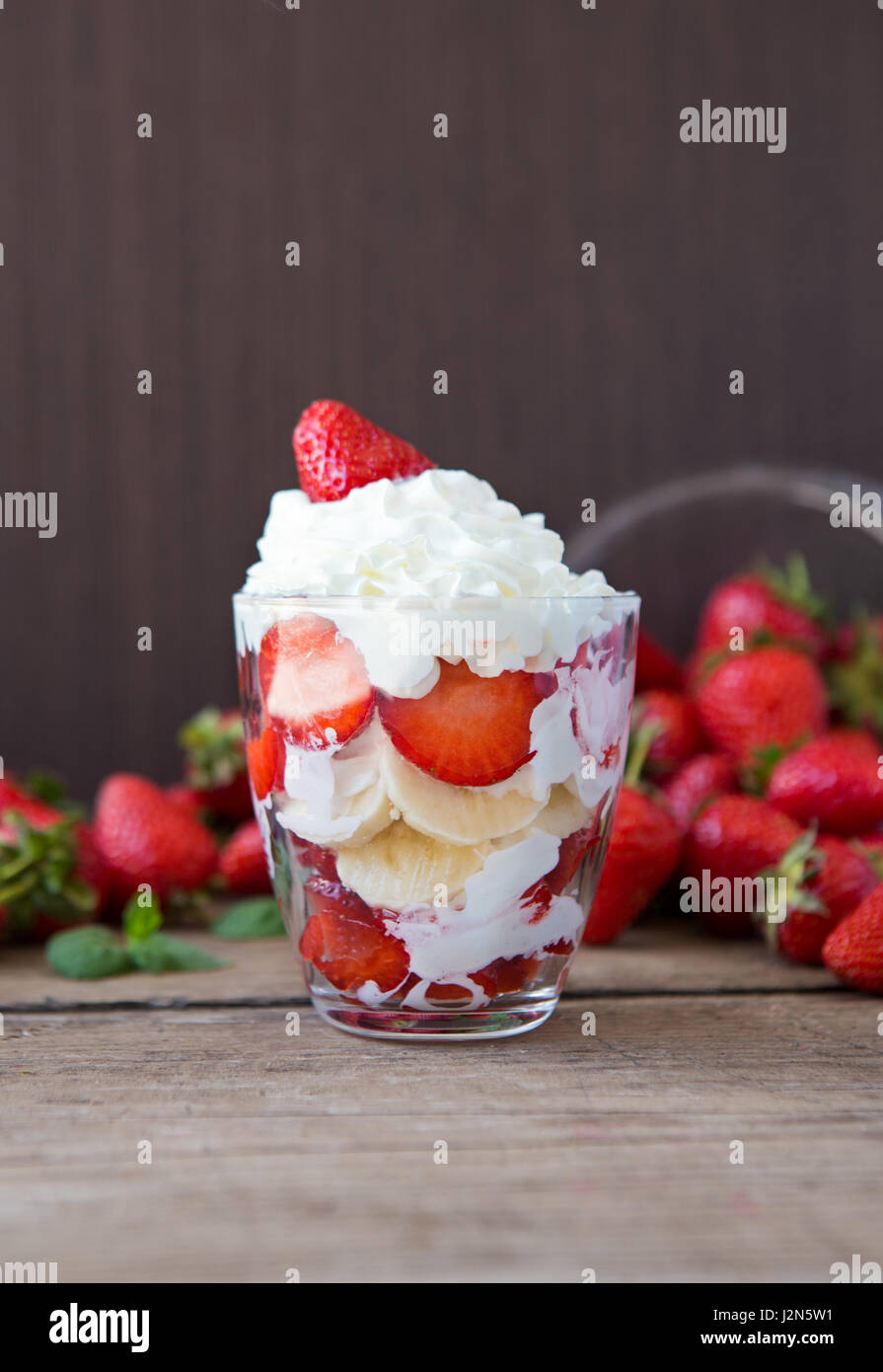 Fresh strawberries and banana dessert layered with whipped cream Stock Photo
