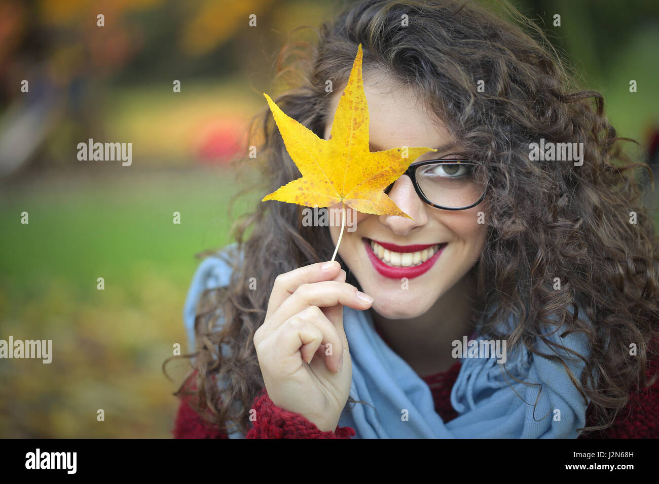 Curly brunette woman holding a leaf to her face Stock Photo