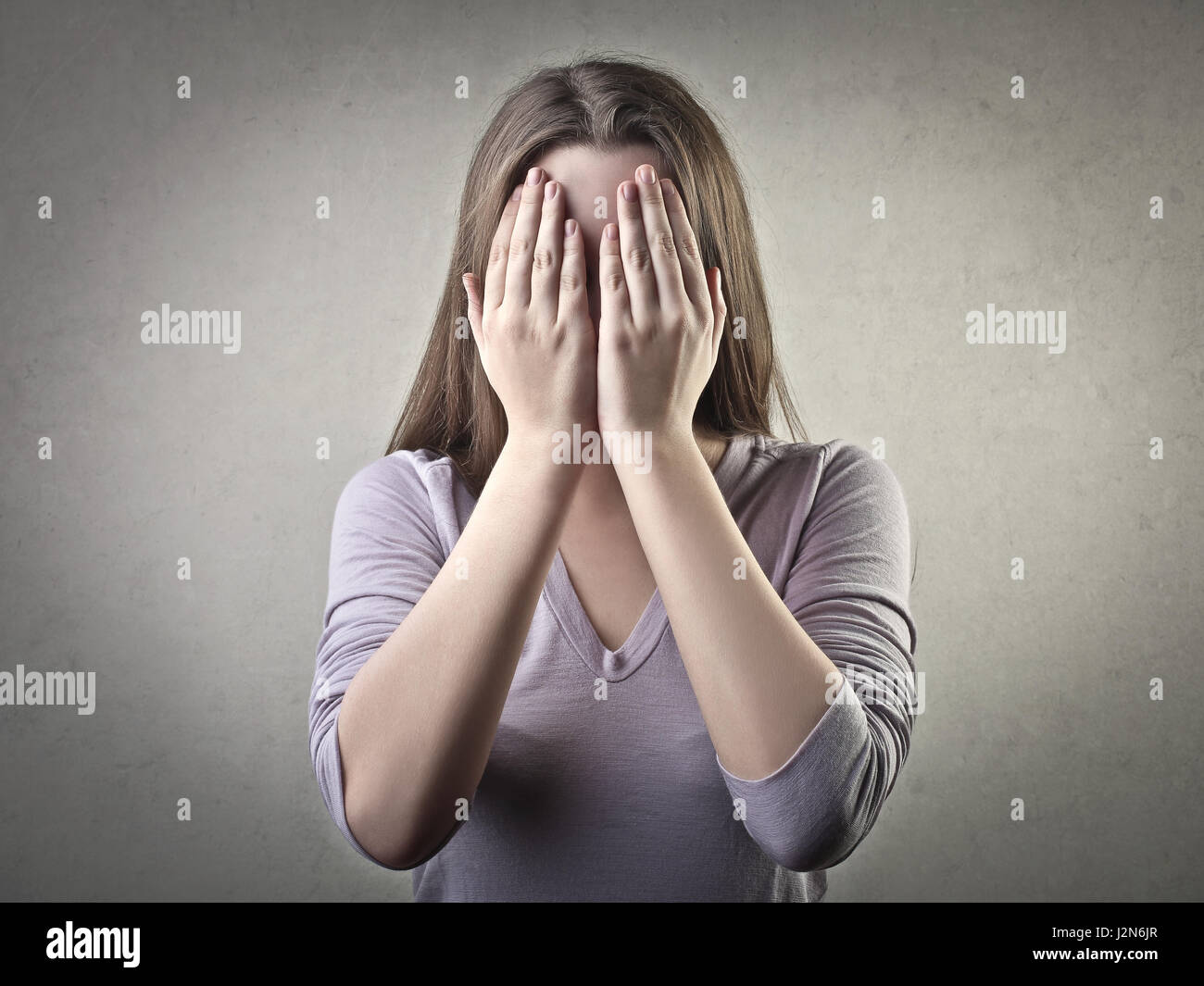 Woman covering her face with her hands Stock Photo