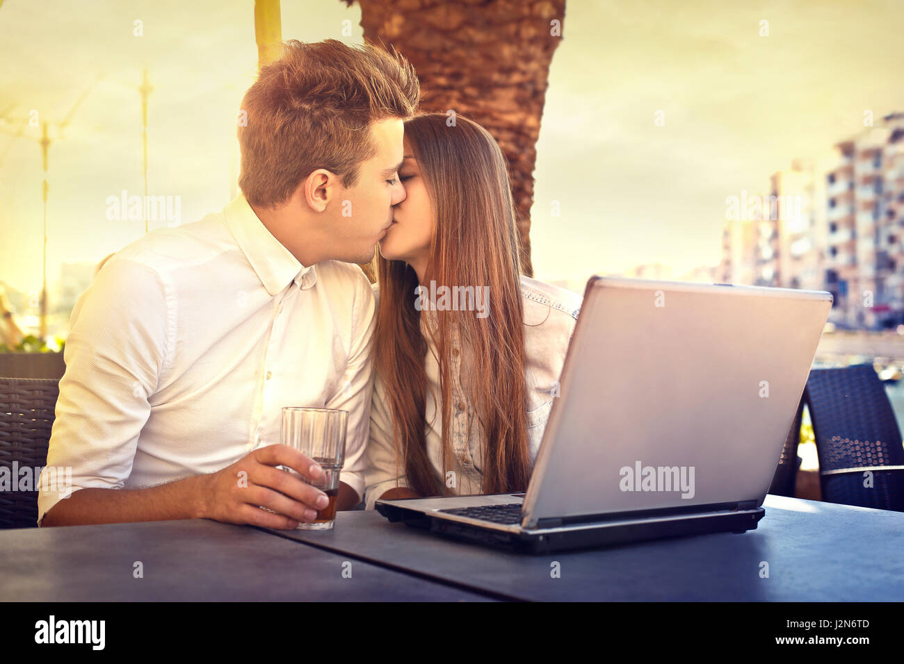 Young couple kissing in front of laptop Stock Photo