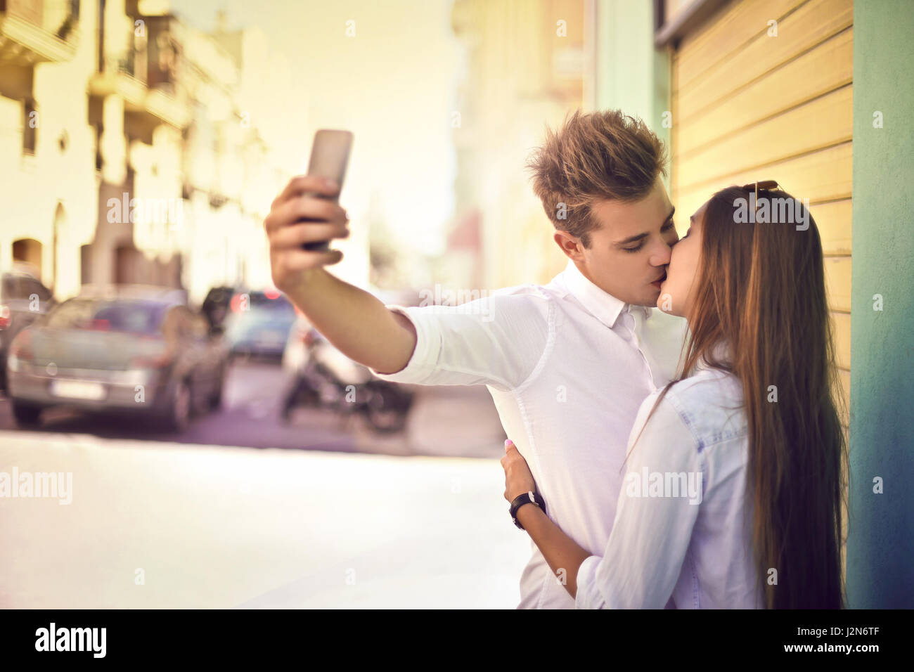 Young couple kissing outside and taking a selfie Stock Photo