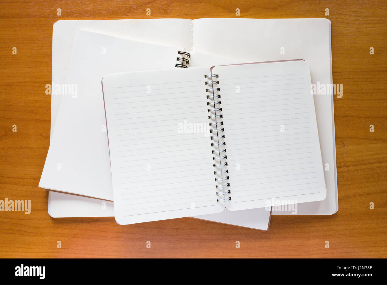 Stack of three empty white notebooks on wooden desk Stock Photo - Alamy