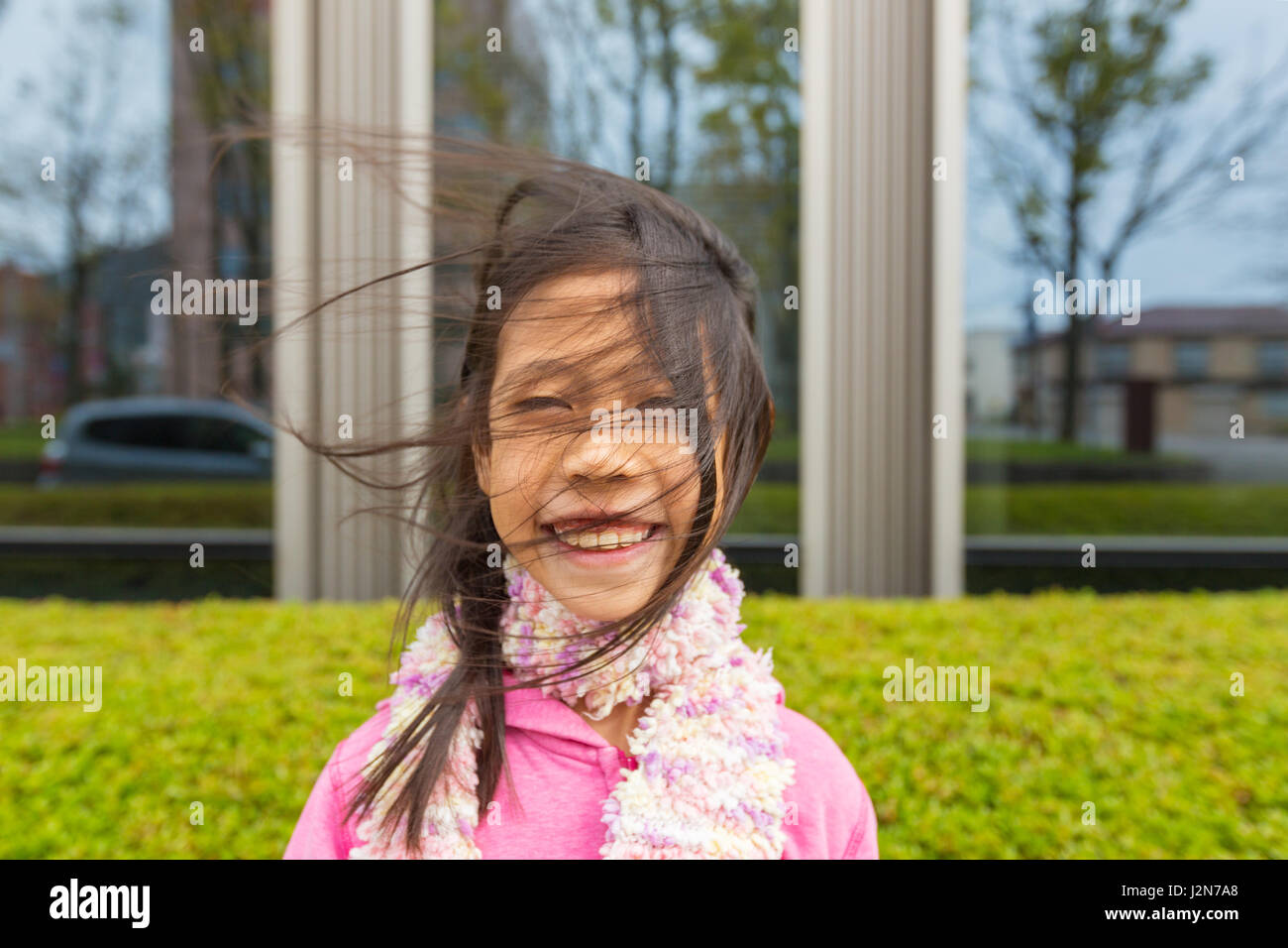 Side wind blowing happy and smiling asian's girl hair in a spring cold day, selective focus on the hair in front of the girl's face Stock Photo