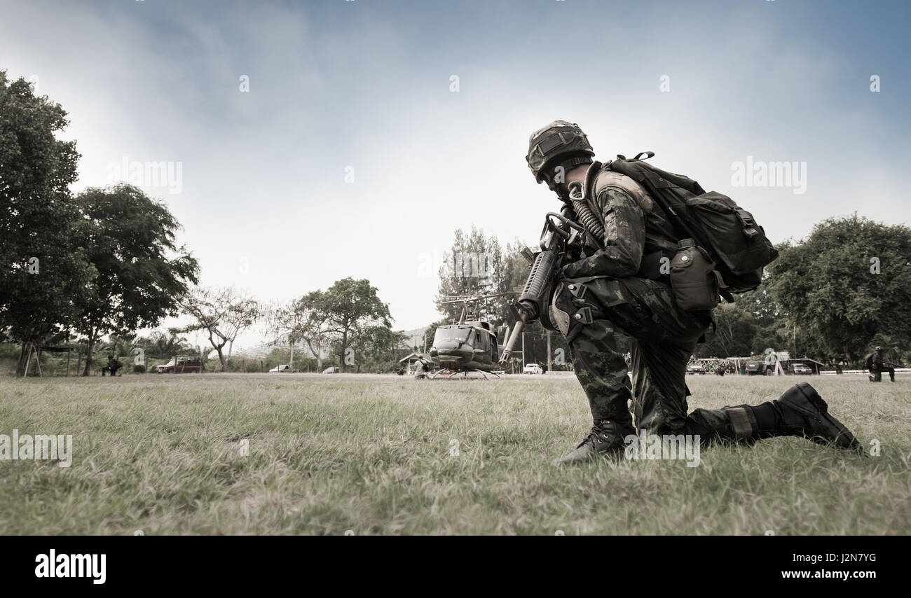 Thai Army rangers with rifle gun in full uniform preparing to jump over the helicopter at the open field operation site Stock Photo