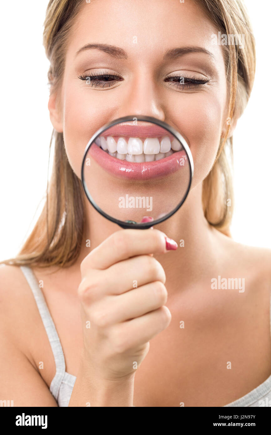 young woman  with perfect smile and healthy  teeth behind magnifying glass Stock Photo