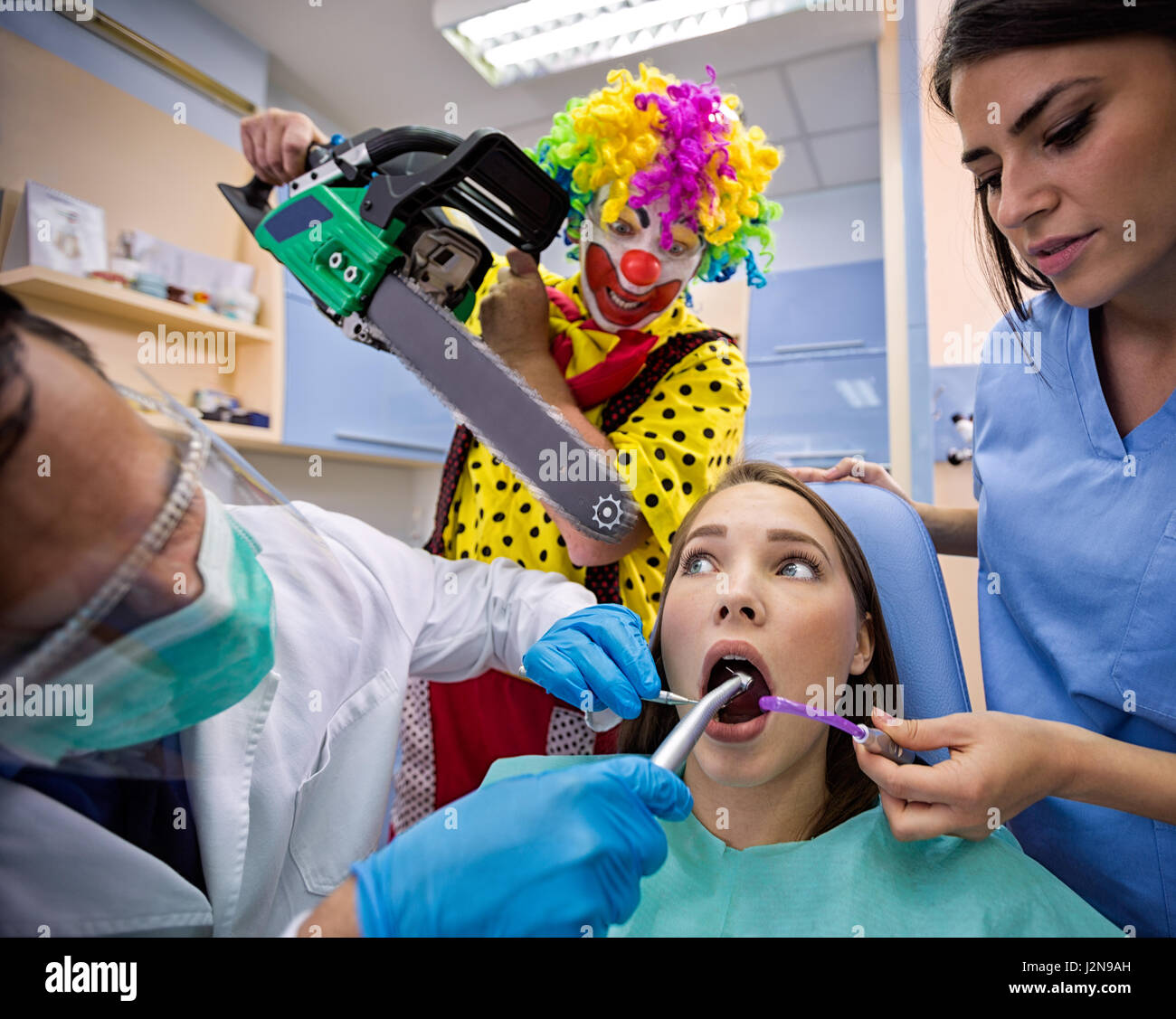 Female patient terrified in dental chair with clown from horror holding