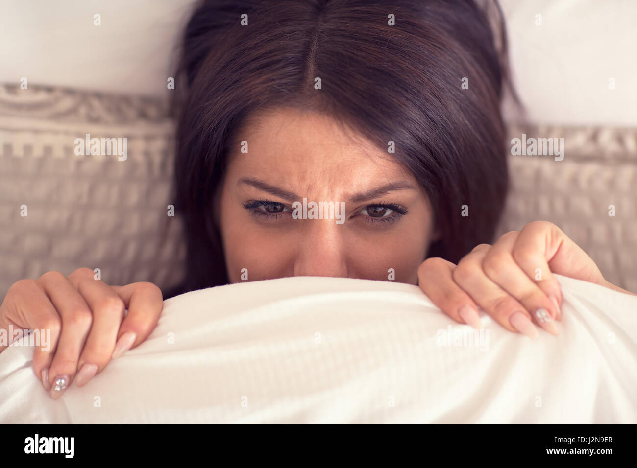 Young pretty female wake up hardly from bed in early morning Stock Photo