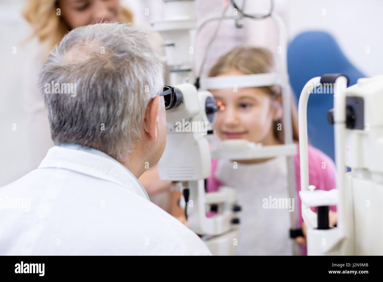 Eye doctor male senior look with eye apparatus in child’s eye Stock Photo