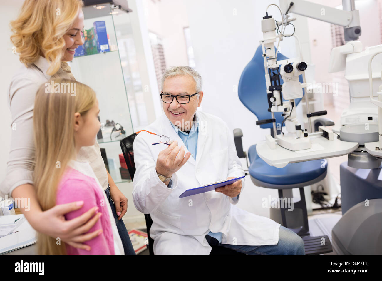 Male doctor speak with his patient with mother in eye clinic Stock Photo