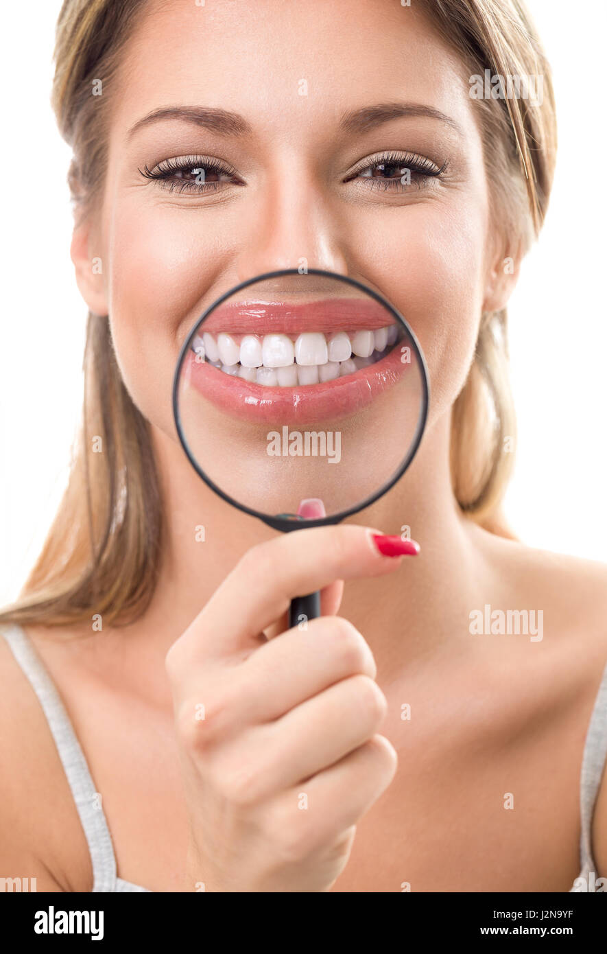 Beautiful woman with magnifying glass showing her perfect white teeth Stock Photo